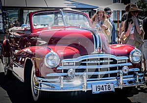 Star-burst sparkles of chrome grill and bumper of red vintage Pontiac