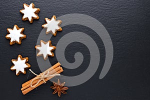 Star cookies on black background with cinnamon, anise and copy space