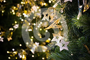 Star hanging on christmas tree with bokeh light in green yellow golden color, holiday abstract background, blur defocused