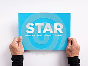 STAR method for business job interviews. Behavioral interviewing response technique. Male hand holding a blue paper with the word
