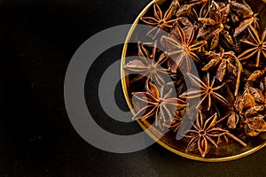 Star shape anis seeds in bowl on black slate