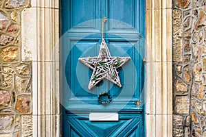 A star-shape Christmas decoration hanging on a blue front door