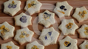 Star shaped biscuits decorated with edible flowers, pansies and cornflower petals.