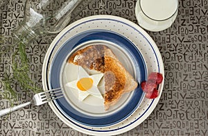 Star shaped fried egg and toast with strawberries on the side sitting in a white plate with a blue rim