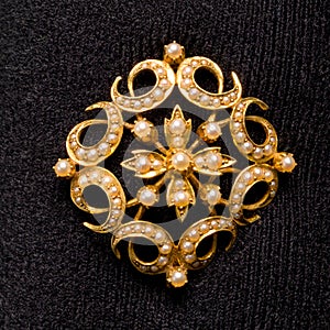 Star shaped pearl inlaid broach or shawl pin Gold in colour with pearls inlaid around the broach Set on a jewellery display