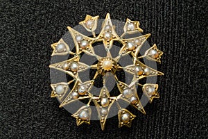 Star shaped pearl inlaid broach or shawl pin Gold in colour with pearls inlaid around the broach Set on a jewellery display