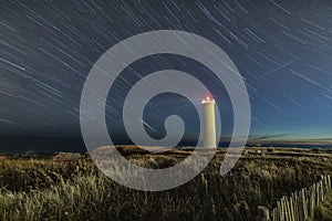 Star trails above lighthouse