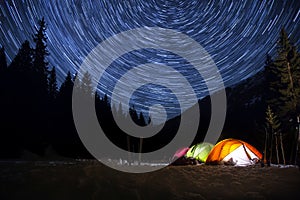 Star trails in the night sky above the tent. Time-lapse.