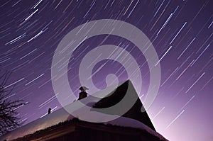 Star trails over the house late at night, purple night sky,