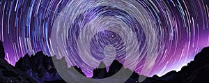 Star trails over mountain peaks at night