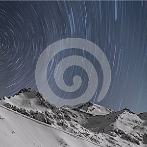 Star trails, snow capped mountains