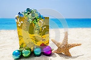 Starfish with Christmas balls and gift on the beach - holiday co