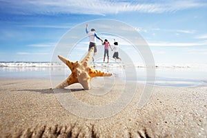 Starfish In Foreground As Father Plays With Children In Sea