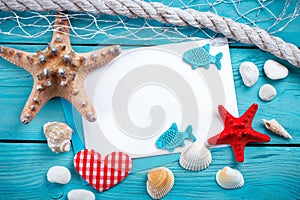 Starfish, pebbles and shells lying on a blue wooden background with postcard. There is a place for labels.