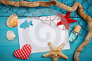 Starfish, pebbles and shells lying on a blue wooden background with postcard. There is a place for labels.