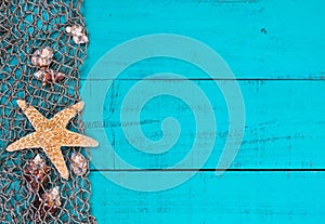 Starfish and shells in fish netting on teal blue wood sign