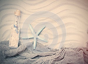 Starfish, souvenir bottle and fishnet on the sand