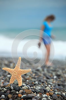 Starfish and young girl on stone seacoast