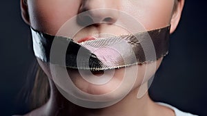 The mouth, taped shut, symbolizes the suppression of free speech. This stark representation highlights the struggle for self- photo
