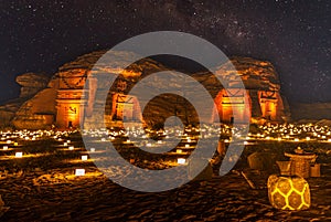 Starlight sky over the ancient nabataean tombs of Hegra city illuminated, night panorama, Al Ula, Saudi Arabia photo