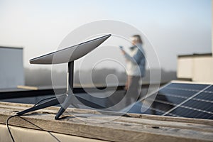 Starlink satellite dish on roof of residential building and woman on background