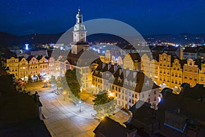 Starry evening over Jelenia Gora market square. Beautiful illuminated town hall building, old tenement houses and restaurants