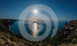 Starry night with a full moon over sea, yachts and rocks in front. Cape Fiolent, Orest and Pilad rocks on the background of the