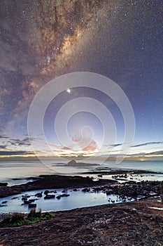 Starry night sky just before sunrise of coastal landscape