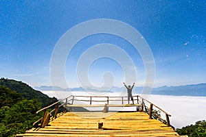 Starry night sky with standing man on bamboo terrace in front of mountains at Gloselo
