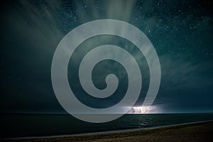 Starry night with thunderstorm and lightning over the sea