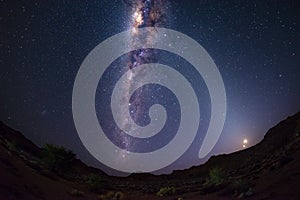 Starry sky and Milky Way arch with moon in the Namib desert in Namibia, Africa. The Small Magellanic Cloud on the left hand side.