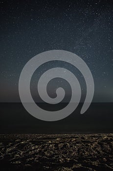 Starry sky on the sea coast, the Milky Way, in the foreground a beach made of shells