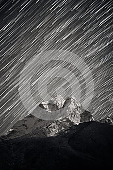Stars falling above Ama Dablam mountain peak lit up by a bright moonlight. Stars trails above Himalayan mountain range.