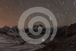 Stars falling above Himalayan mountain range lit.