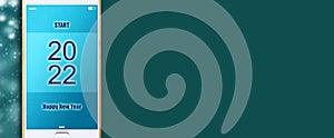 2022. Start. Button on a smartphone, on a green background. Concept for the start of the New Year 2022. Copy space