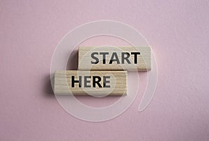Start here symbol. Wooden blocks with words Start here Beautiful pink background. Business and Start here concept. Copy space