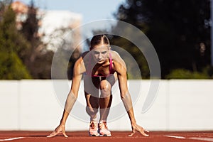 At start line. One Caucasian woman, female athlete, runner training at public stadium, sport court or palyground