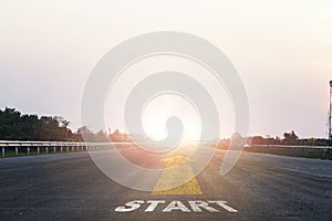 Start line wording with yellow arrow to glowing sunlight on super high way for business and challenge plan of career path concept