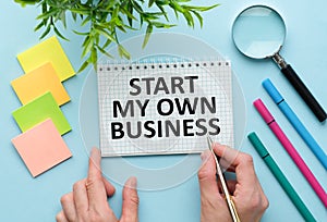 Start My Own Business text written in Notebook, Business concept, blue background, Pencil, Notebook and calculator