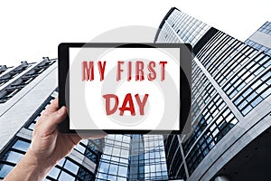 Start new job. Man holding tablet with text My First Day against building, closeup