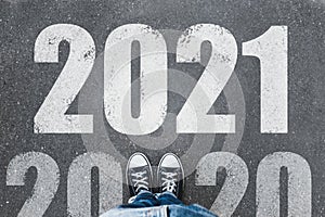 Start new year with fresh vision and ideas. 2021 numbers on asphalt road in front of woman, top view