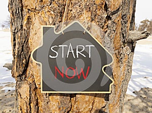 Start now symbol. Concept words Start now on beautiful black house blackboard. Beautiful tree background. Business marketing,