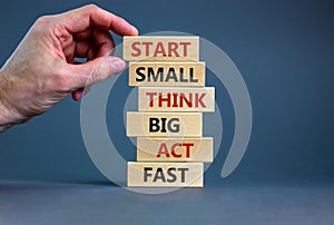 Start small think big symbol. Words `Start small think big act fast` on wooden blocks on a beautiful grey background. Businessma