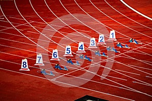 Start of sprint race. Numbers and starting blocks on the red track. Athletics stadium. Track and field photo. Starting numbers on