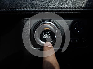 Start-Stop engine button with orange light on black car console background