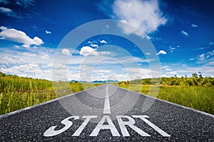 Start text on long road with green field and blue sky