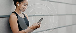 Start training and music for jogging. African american girl with wireless headphones looks in smartphone