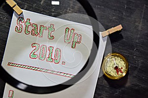 Start Up 2019 handwritten text on the paper with marker, compass and use magnifying glass