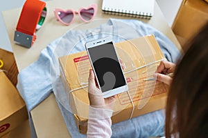 Start up business owner writing customer address on the box with her online selling product on the desk. Woman seller prepare