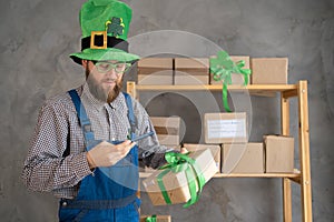 start up. businessman scanning a delivery box with his mobile phone. Man in leprechaun hat selling products online